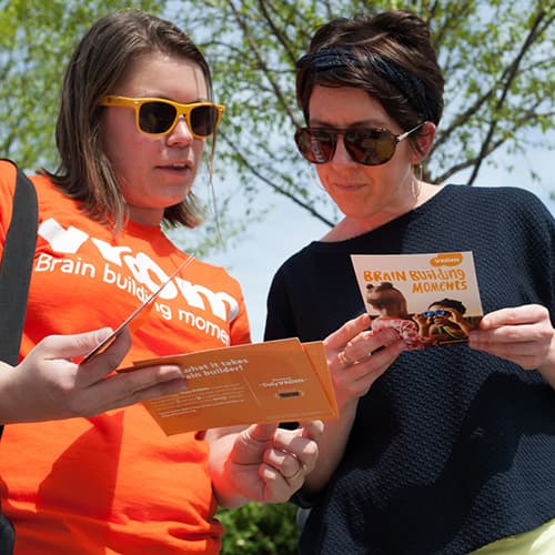 A Vroom representative sharing Vroom materials with a mother.